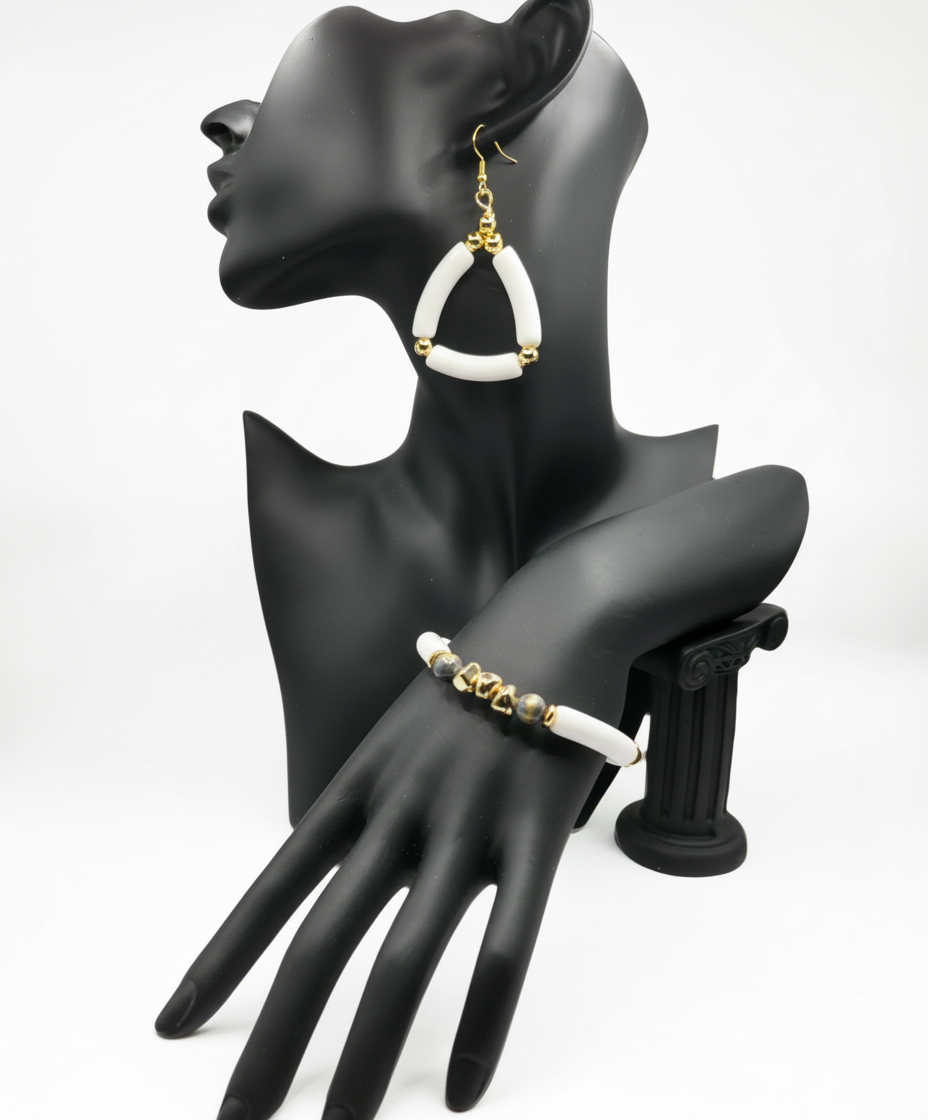 Mannequin hand wearing gold and white hoop earrings and bracelet on a gray background