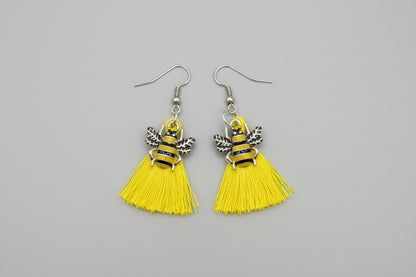 Yellow tassel earrings with bee designs on a gray background