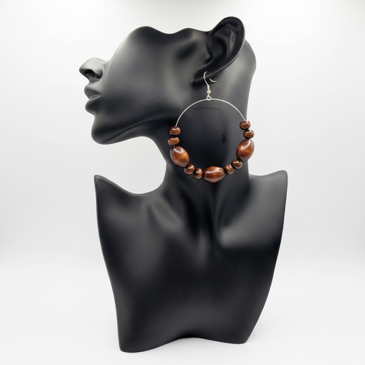 A pair of wood hoop earrings displayed on a mannequin head, with the earrings featuring a series of wooden beads attached to a metal hoop.