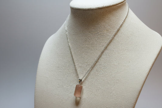 Necklace with a cherry quartz pendant on a mannequin bust against a neutral background