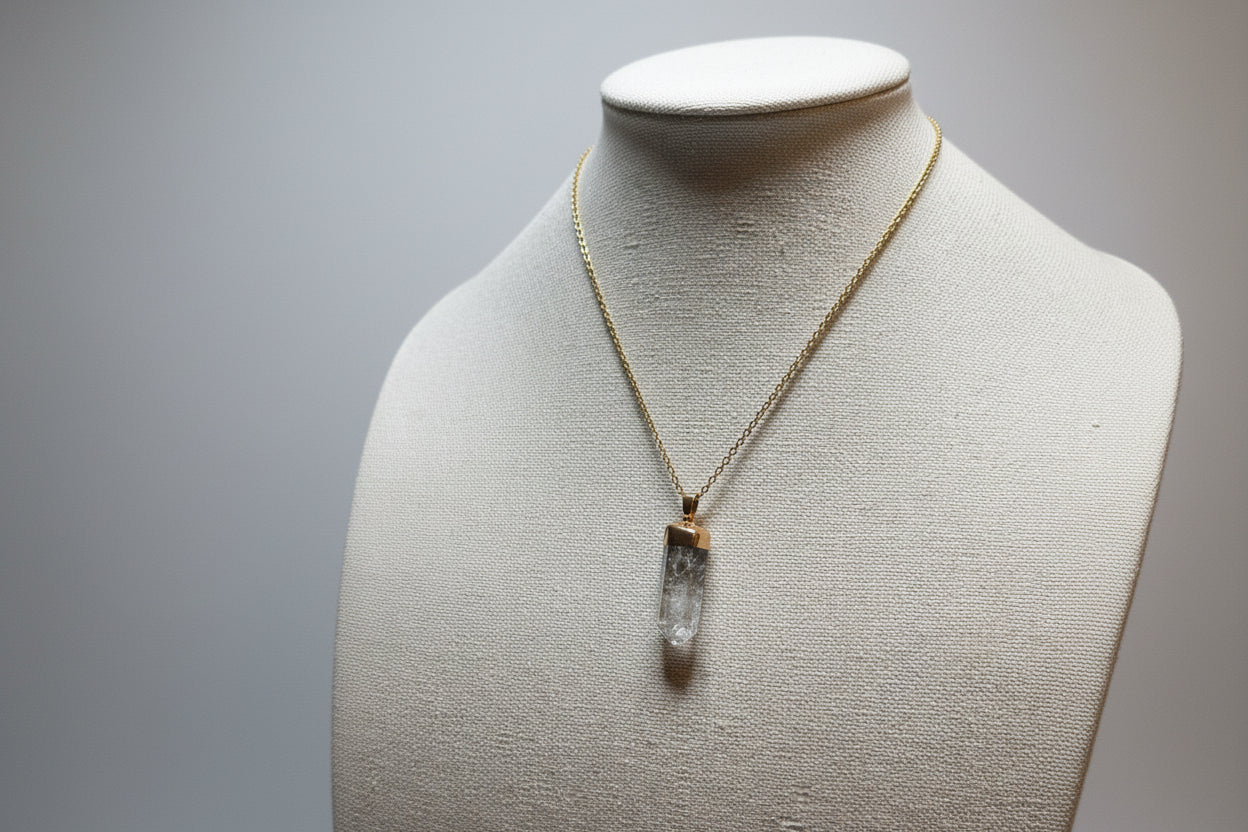 Necklace with a clear pendant on a mannequin bust against a plain background