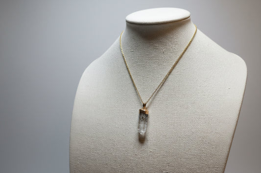 Necklace with a clear pendant on a mannequin bust against a plain background