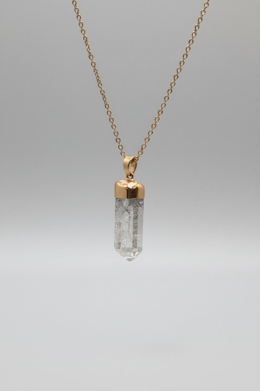 Necklace with a gold pendant and clear crystal on a gray background
