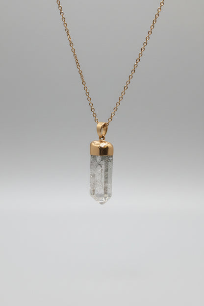 Necklace with a gold pendant and clear crystal on a gray background