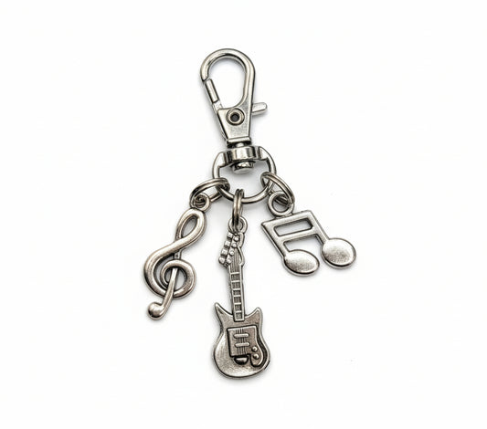 Silver keychain with musical charms on a white surface