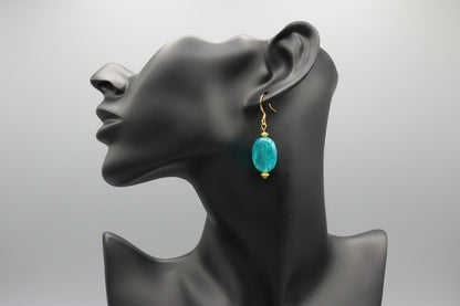 Mannequin head with a turquoise earring on a blurred background