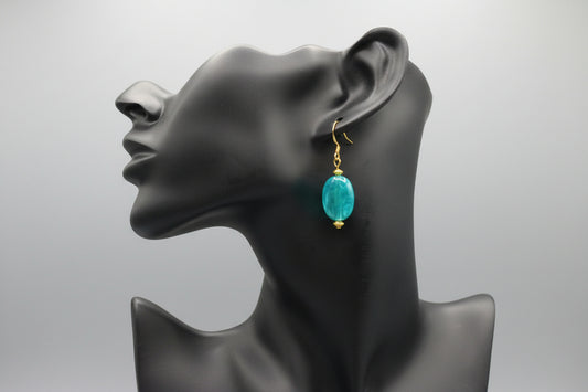 Mannequin head with a turquoise earring on a blurred background