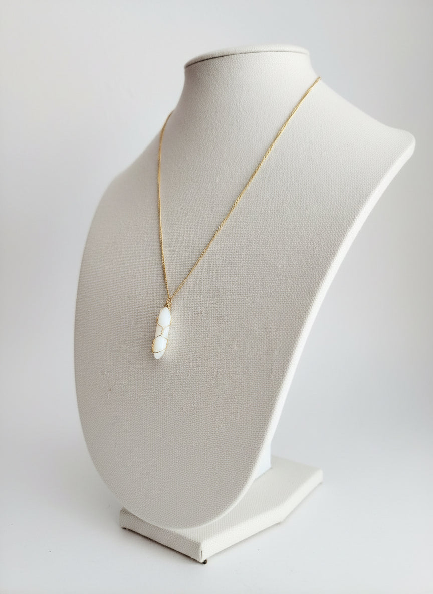 Necklace with a large white gemstone pendant on a linen mannequin bust against a white background